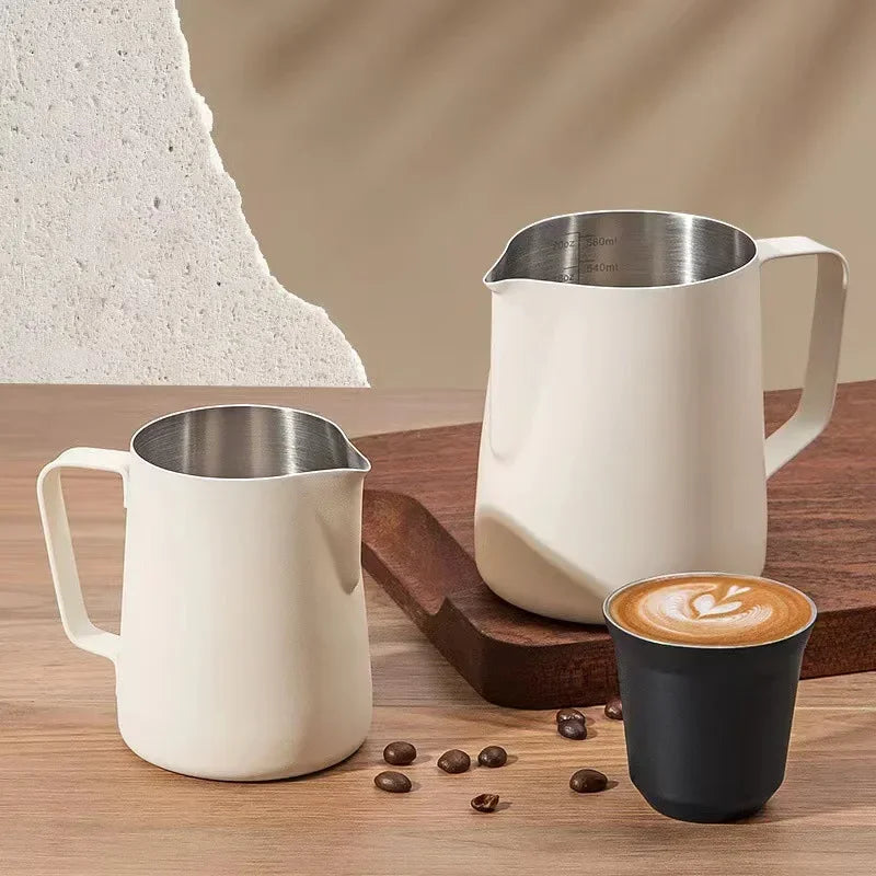 To hvide mælkekander i metal med hank og indvendig skala samt en lille kop kaffe og kaffebønner.